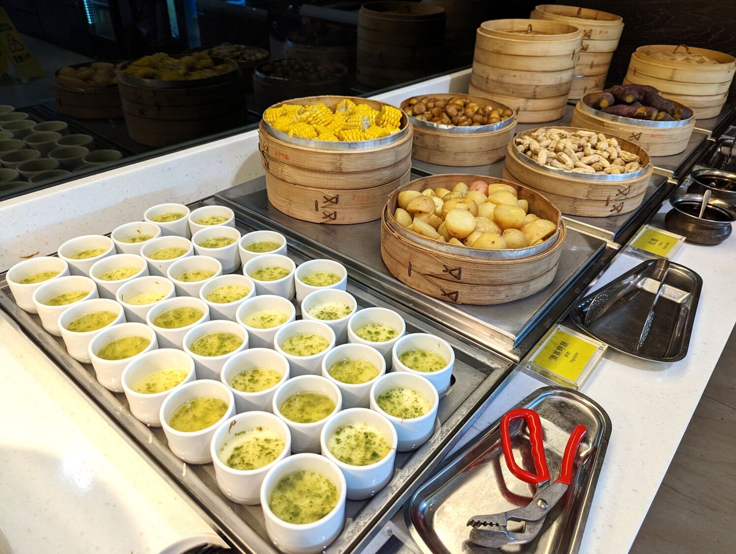 Un bufé con diversos alimentos en cestas y recipientes, como maíz, nueces y una salsa verde.