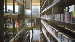 A modern library with glass floors, bookshelves, and a view of the city. - The Walden (Yilan)