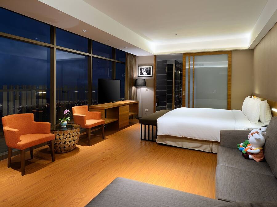 Una habitación de hotel moderna con una cama grande, un sofá, un escritorio y un televisor.