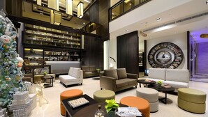 A modern, multi-level living space with a large Christmas tree, comfortable seating, and a prominent circular bookshelf. - The Walden (Yilan)