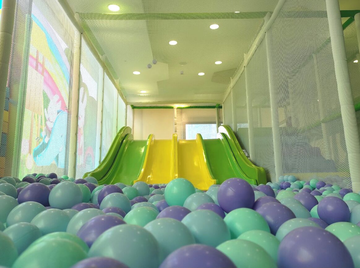 Zona de juegos con dos toboganes y un foso de pelotas de colores.