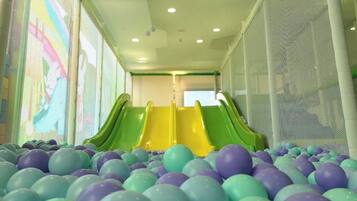 Zona de juegos con dos toboganes y un foso de pelotas de colores.