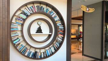 A circular bookshelf with books arranged in concentric circles, a clock in the center, and a directional sign on the wall.