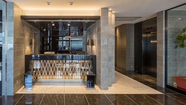 A modern lobby with a reception desk, two elevators, and a glass wall. - Hotel Links Namba (Osaka)