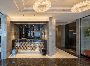 A modern lobby with a reception desk, two elevators, and a glass wall. - Hotel Links Namba (Osaka)
