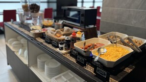 A buffet with various food items and condiments, including scrambled eggs, sausages, and a variety of sauces. - Hotel Links Namba (Osaka)