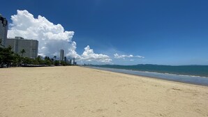 Ein weiter Sandstrand mit blauem Himmel und Bergen in der Ferne.