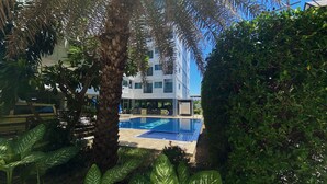 Ein Poolbereich mit klarem, blauem Pool, umgeben von üppiger Vegetation und einem modernen Gebäude im Hintergrund.