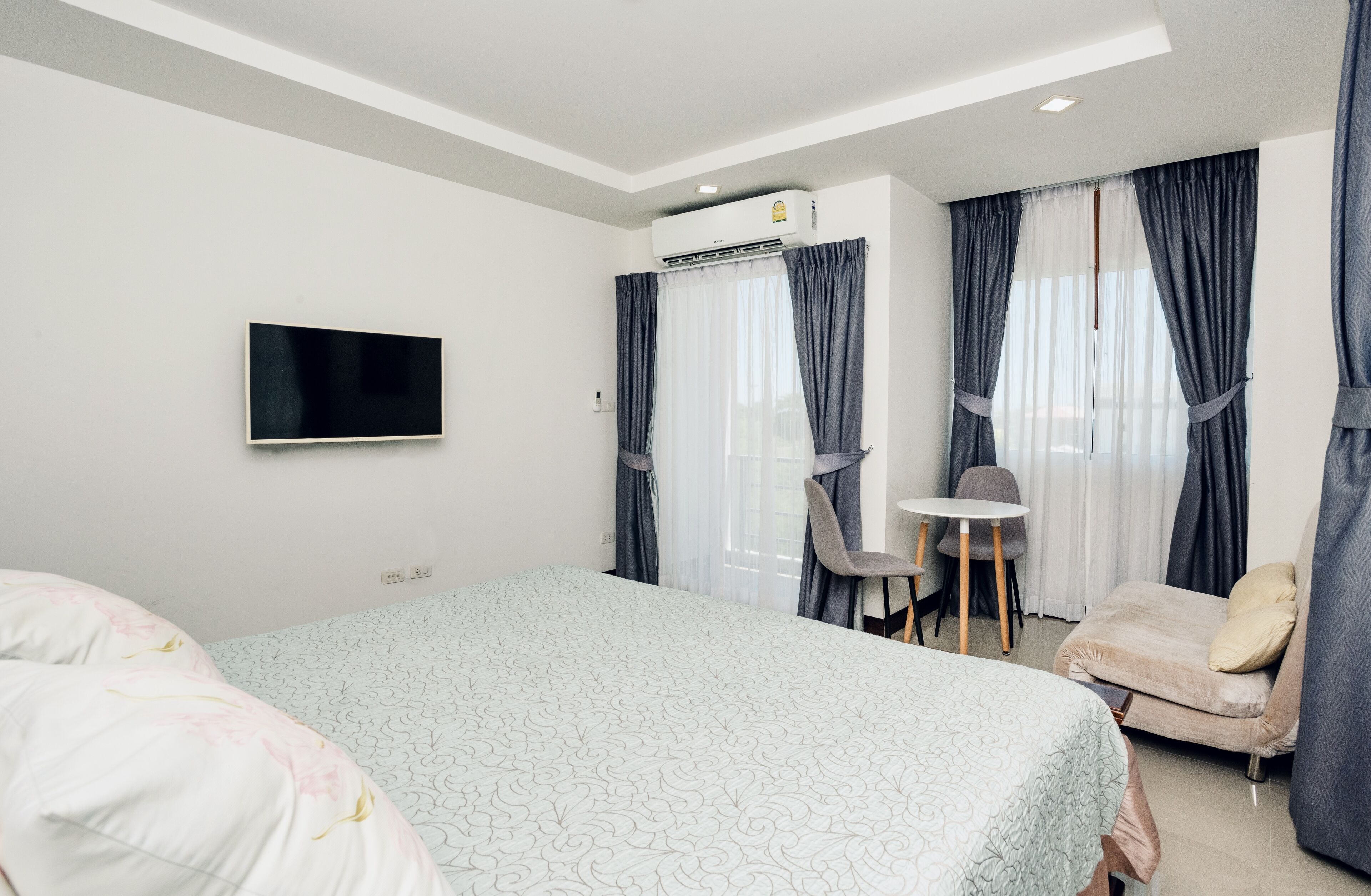 Een hotelkamer met een bed, een bureau, een stoel en een aan de muur bevestigde televisie.