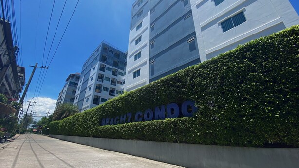 Ein modernes Gebäude mit einer Hecke und einem Schild, auf dem "BEAUX CONDO" steht.