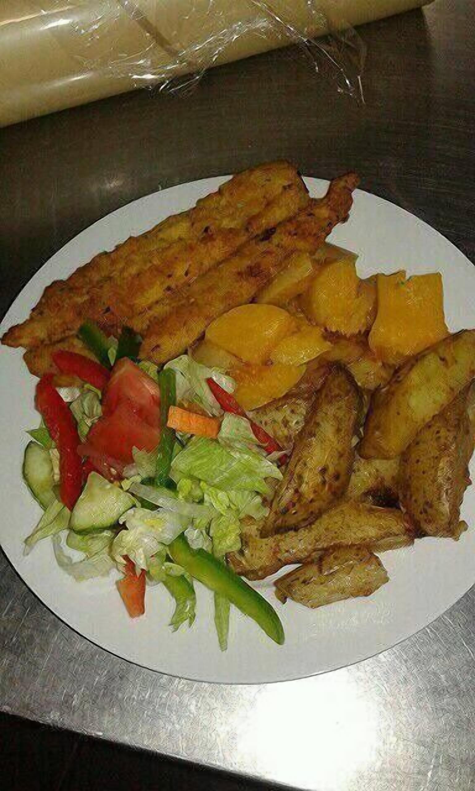 Un plato con pescado frito, boniato y una ensalada.