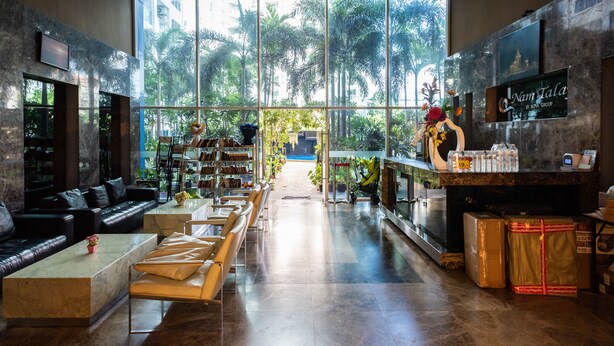 A spacious lobby with a modern design, featuring a seating area with sofas and chairs, a reception desk, and large windows offering a view of the outdoors.