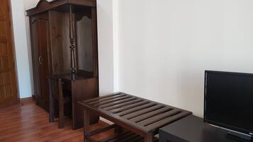 A room with a wooden bench, a TV stand, and a wooden wardrobe.