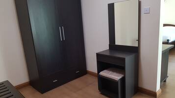 A room with a large wardrobe, a vanity with a mirror, and a small bench.