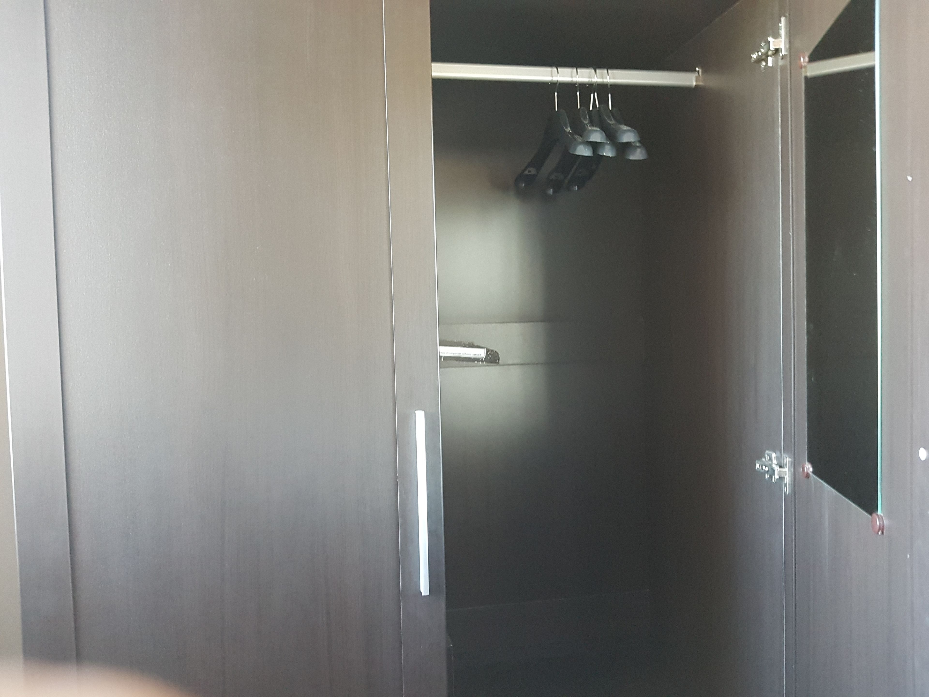 A walk-in closet with a hanging shoe rack and a visible door handle.