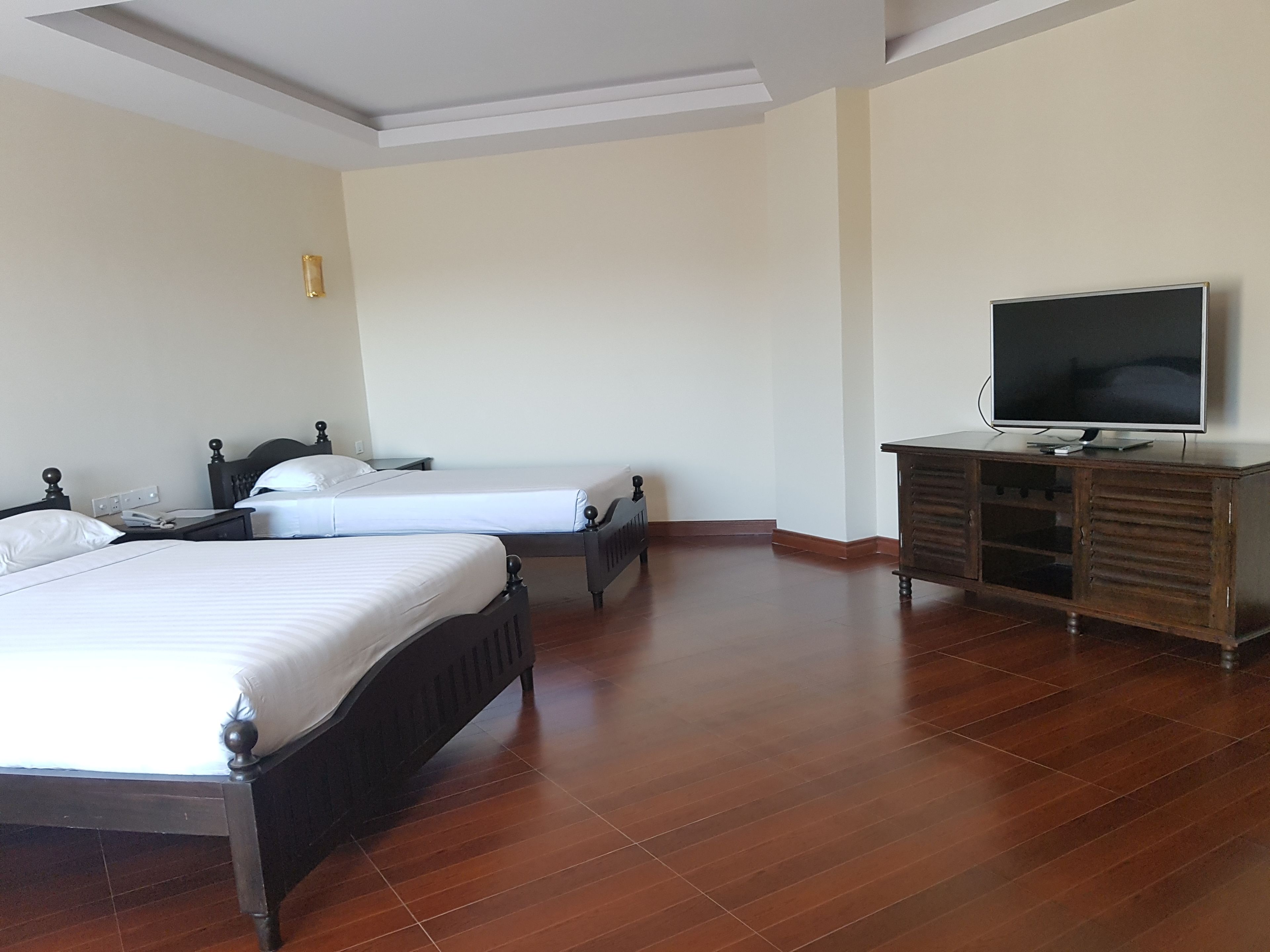 Une chambre d’hôtel avec deux lits, une commode en bois et un téléviseur.