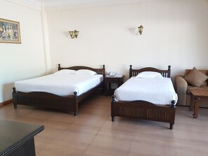 Ein Hotelzimmer mit zwei Holzbetten, einem kleinen Schreibtisch mit Telefon und einem Nachttisch.