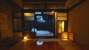 A traditional Japanese room with tatami flooring, a wooden table, and a sliding door leading to a room with a bed and a view of the cityscape. - Kiraku Kyoto Aneyakoji (Kyoto)