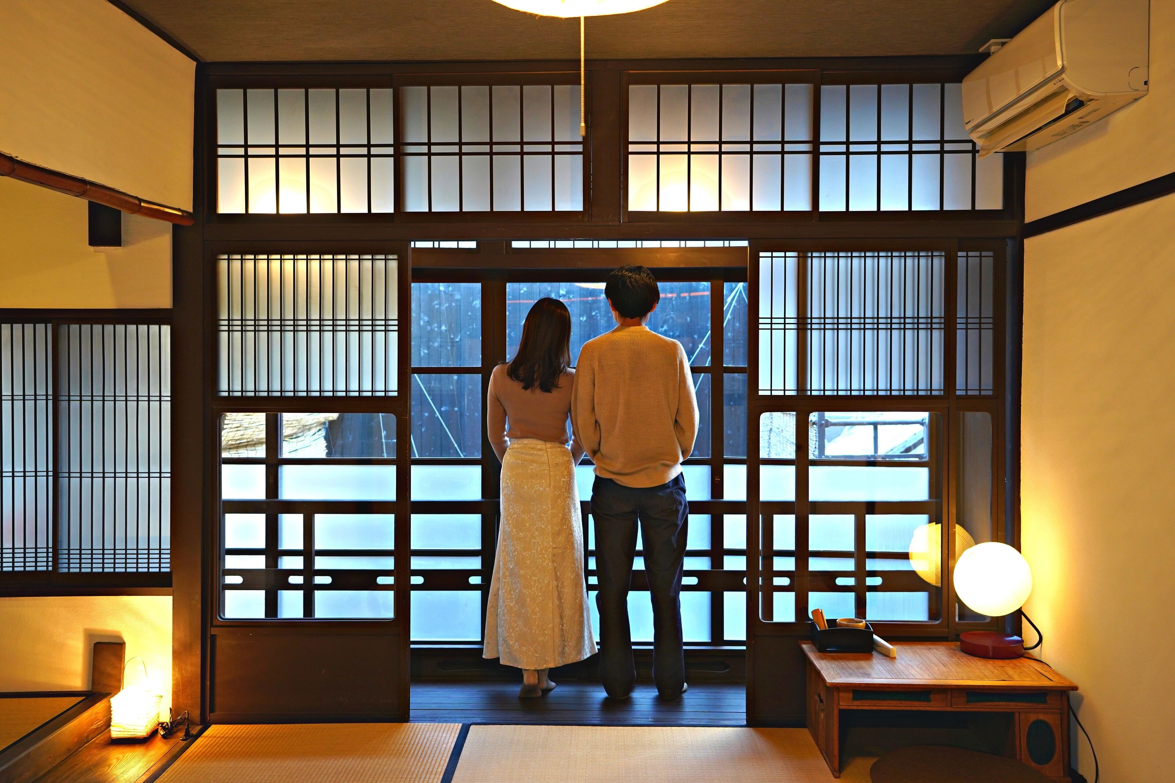 Una habitación japonesa tradicional con suelo de tatami, un escritorio de madera bajo y una puerta corredera de shoji.