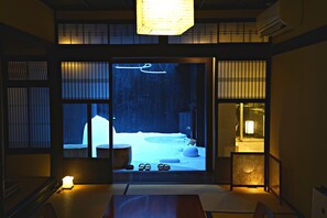 A traditional Japanese room with tatami flooring, a low table, and a sliding door leading to a snow-covered garden. - Kiraku Kyoto Aneyakoji (Kyoto)