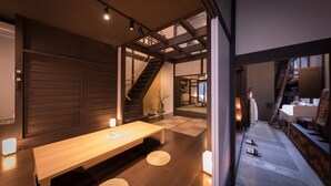 A modern interior with a wooden bench, a staircase, and a view of a kitchen area. - Kiraku Kyoto Aneyakoji (Kyoto)