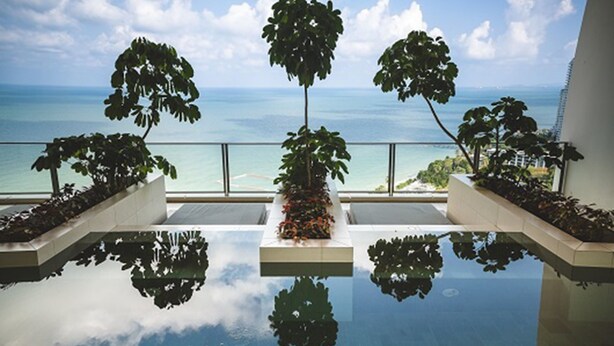 A reflective infinity pool with a view of the ocean and palm trees. - NorthPoint Pattaya Luxury Apartments by GrandisVillas (Pattaya)