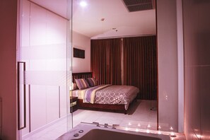 A modern bedroom with a large bed, a glass partition, and a bathtub. - NorthPoint Pattaya Luxury Apartments by GrandisVillas (Pattaya)