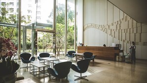 A modern interior with a reception desk, seating area, and large windows. - NorthPoint Pattaya Luxury Apartments by GrandisVillas (Pattaya)