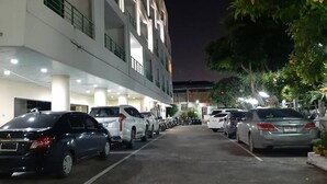A parking area with multiple cars and a building with balconies. - Central Place Hotel (Rayong)