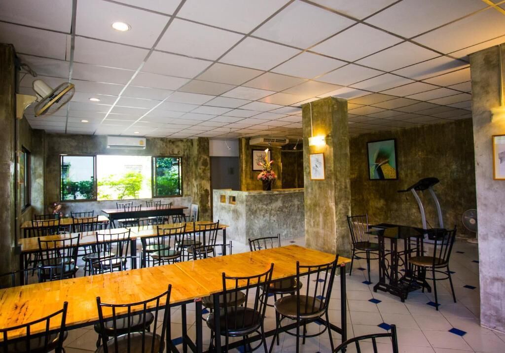 Un restaurante con varias mesas y sillas de madera, un ventanal grande y un ventilador de techo.