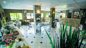 A spacious hotel lobby with a tiled floor, multiple seating areas, and large windows offering views of greenery outside. - Central Place Hotel (Rayong)