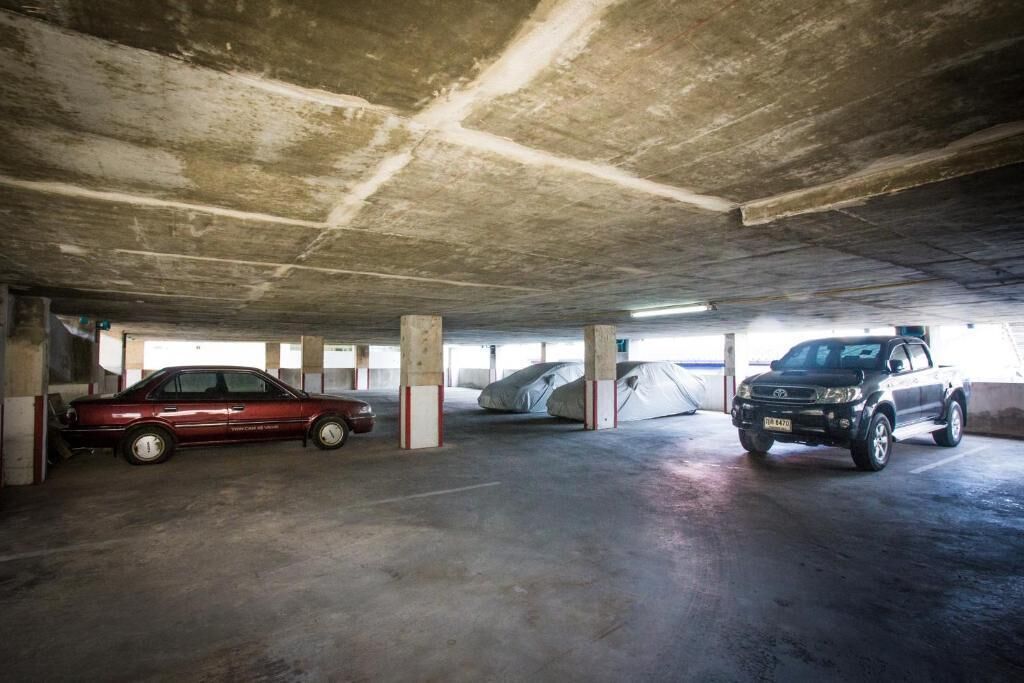 A parking garage with concrete pillars and a car and a pickup truck parked.