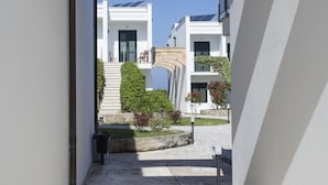 A corridor with a stone archway leading to a white building with a balcony and solar panels. - Hotel Residence Portoselvaggio (Nardò)