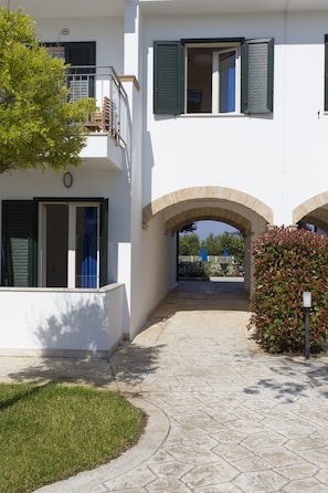 Un bâtiment à deux étages doté d’une entrée pavée, d’un petit jardin et d’une vue dégagée sur l’extérieur, accessible par une arche.