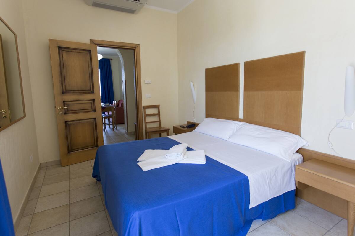 Ein Hotelzimmer mit einem großen Bett, einem Holzkopfstück, einem Nachttisch und einem Sessel.