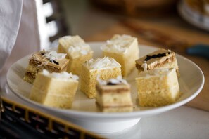 Ein weißer Teller mit verschiedenen quadratischen Kuchenstücken, manche mit Kokosraspeln belegt.