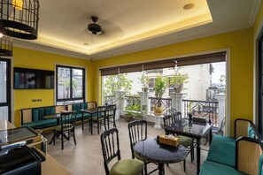 A room with a balcony, a sofa, dining table, chairs, and a ceiling fan. - Hanoi Maro Hotel (Hanoi)
