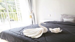 Een slaapkamer met een groot bed, een raam met gordijnen en uitzicht op palmbomen.