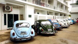 Een rij oldtimers geparkeerd voor een meerlaags gebouw met balkons.