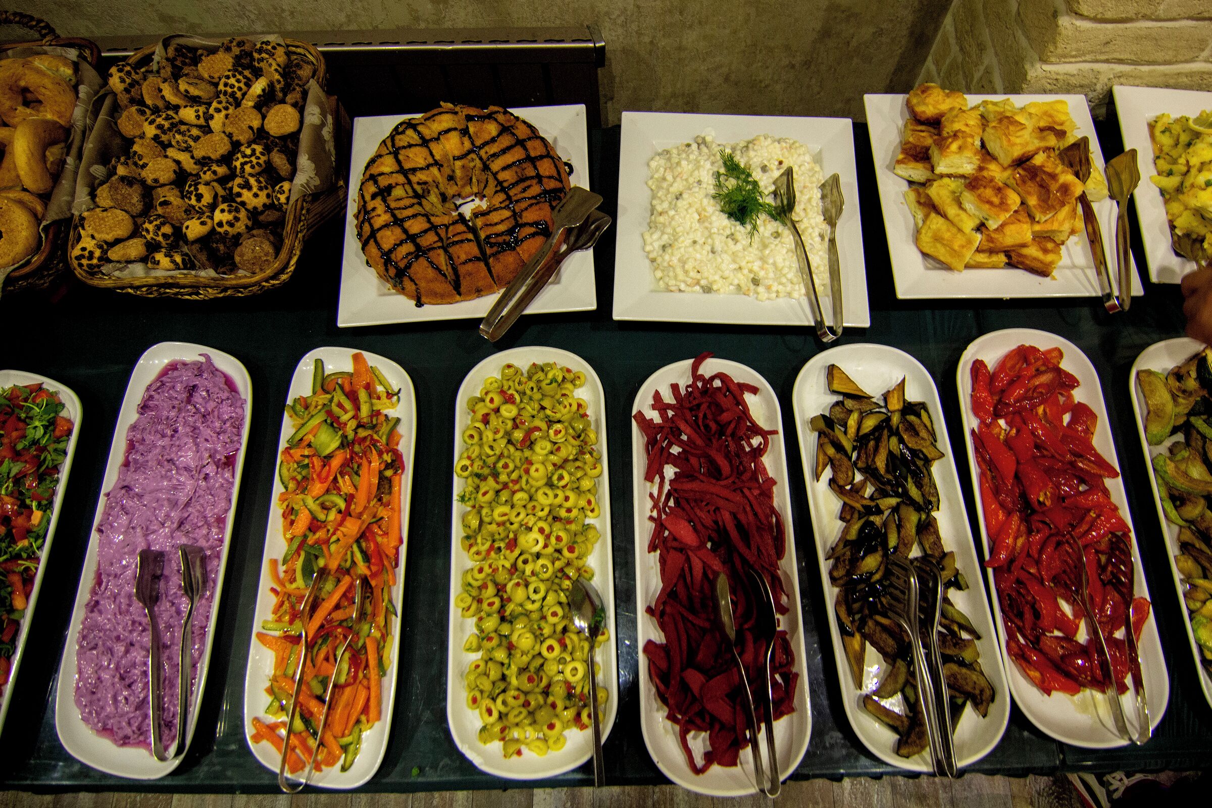 Un buffet proposant une variété de plats, notamment des salades, des légumes et un grand gâteau.