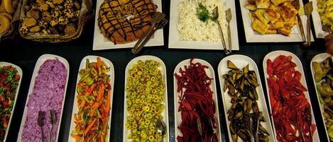 Un buffet proposant une variété de plats, notamment des salades, des légumes et un grand gâteau.