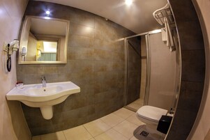 Un baño moderno con lavamanos, espejo, inodoro y ducha.