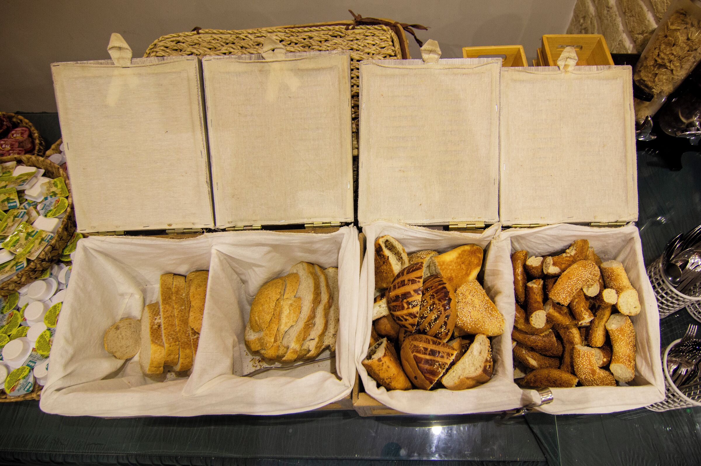 Una mesa con cuatro cestas de pan y pastelería.