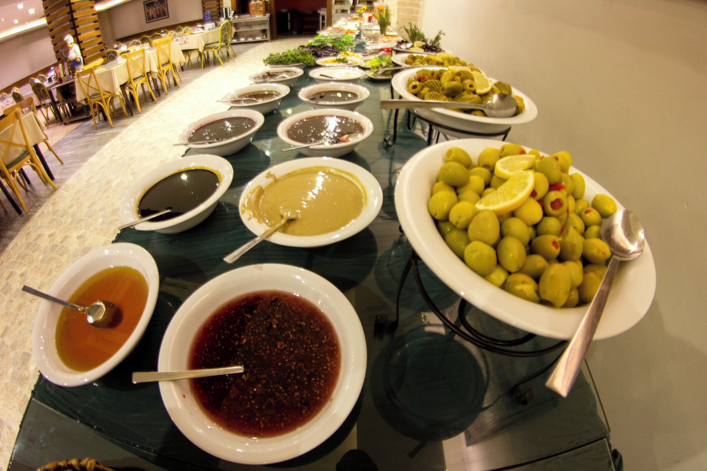 A buffet table with various dishes and condiments.