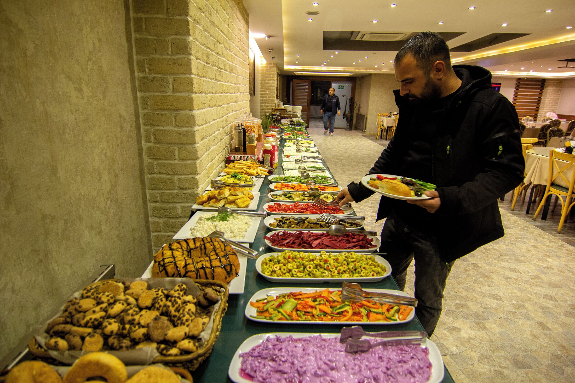 Un bufé con diversos alimentos y una persona servándose.