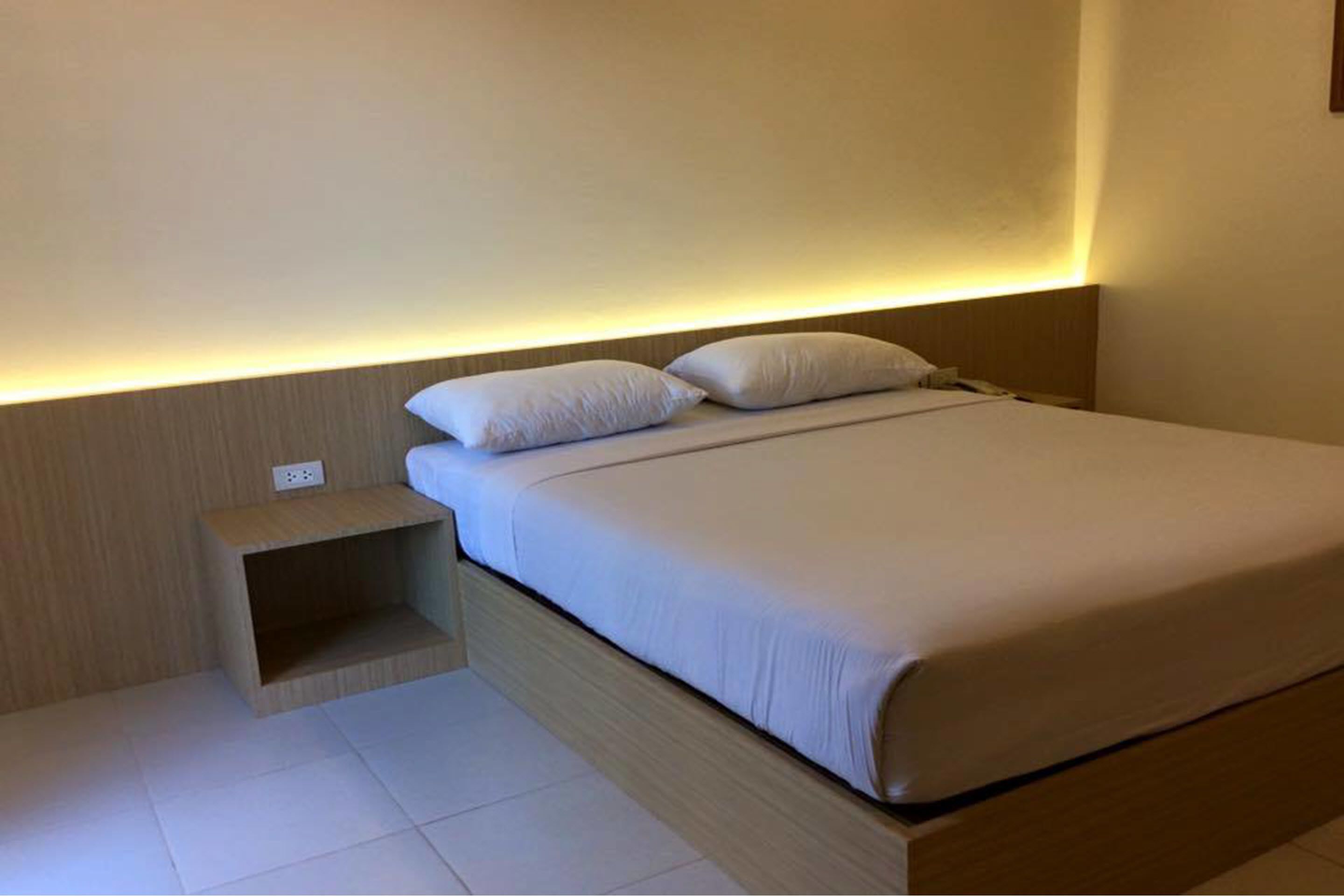A modern bedroom with a bed, bedside table, and a wall-mounted light.