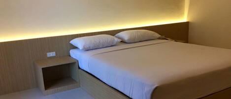 A modern bedroom with a bed, bedside table, and a wall-mounted light.