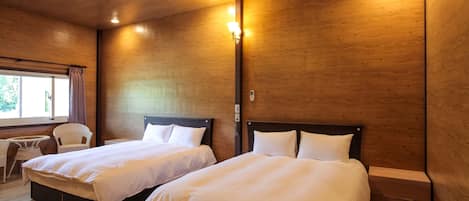 A room with two beds, wooden walls, and a small table with chairs.