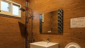 Ein Badezimmer mit Holzvertäfelung, Toilette, Waschbecken und Dusche.
