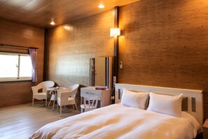 A hotel room with a wooden interior, a bed with white bedding, a desk with a chair, and a window with curtains. - Dream House (Hengchun)